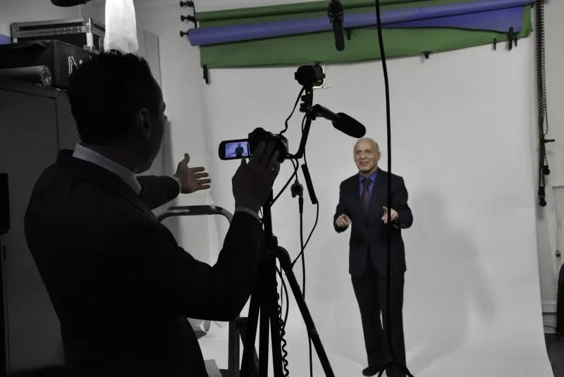 Jess, in silhouette, filming a client against a white studio backdrop